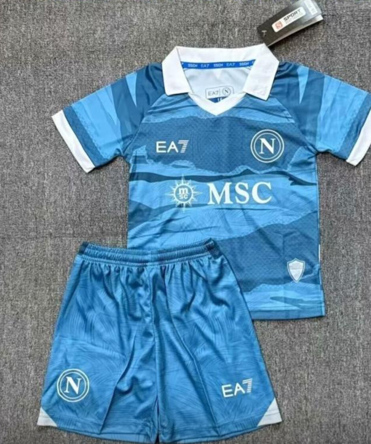 Completino da calcio azzurro con loghi EA7 e MSC.